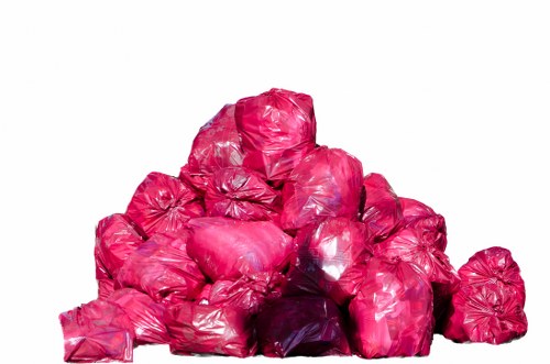 A large pile of bright pink plastic rubbish bags stacked outdoors on a flat surface, with some bags appearing compressed and others loosely gathered, their glossy texture reflecting light. The bags are tightly packed, creating a mound that extends from the foreground to the background, with varied shapes and sizes. The environment suggests an external area such as a driveway or pavement in a residential or commercial setting near Seven Sisters, London, with no visible background landscape or structures. The plastic bags, associated with waste collection and disposal, are characteristic items handled by rubbish removal services such as those offered by Business Waste Removal Seven Sisters. The scene highlights typical bulk rubbish awaiting collection, emphasizing the need for professional waste management to efficiently clear clutter and maintain cleanliness in urban surroundings.